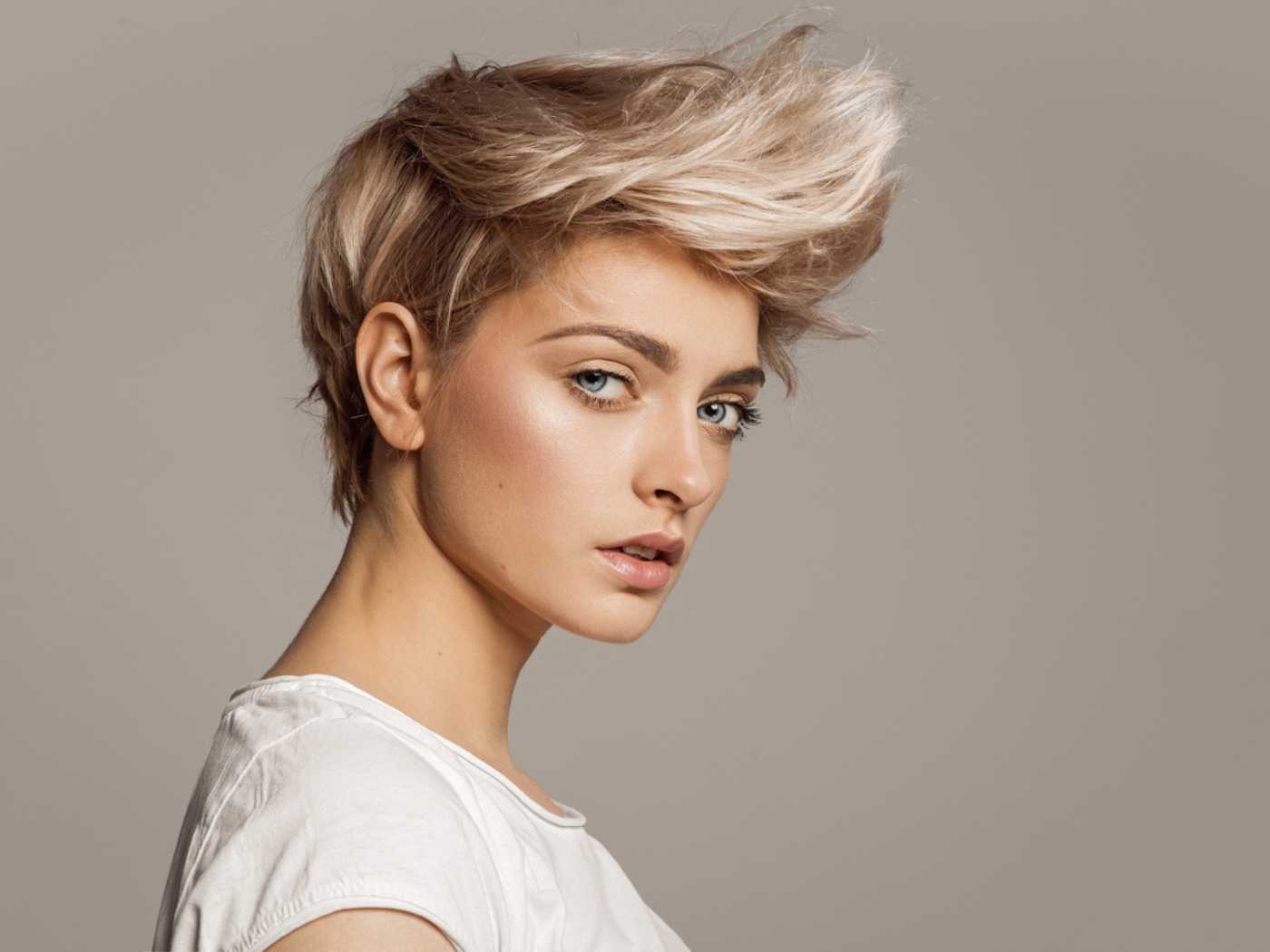 Woman with a pixie haircut facing sideways and looking at the camera