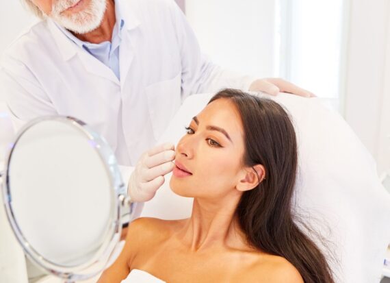 Dermatologist working with a patient as she looks in the mirror