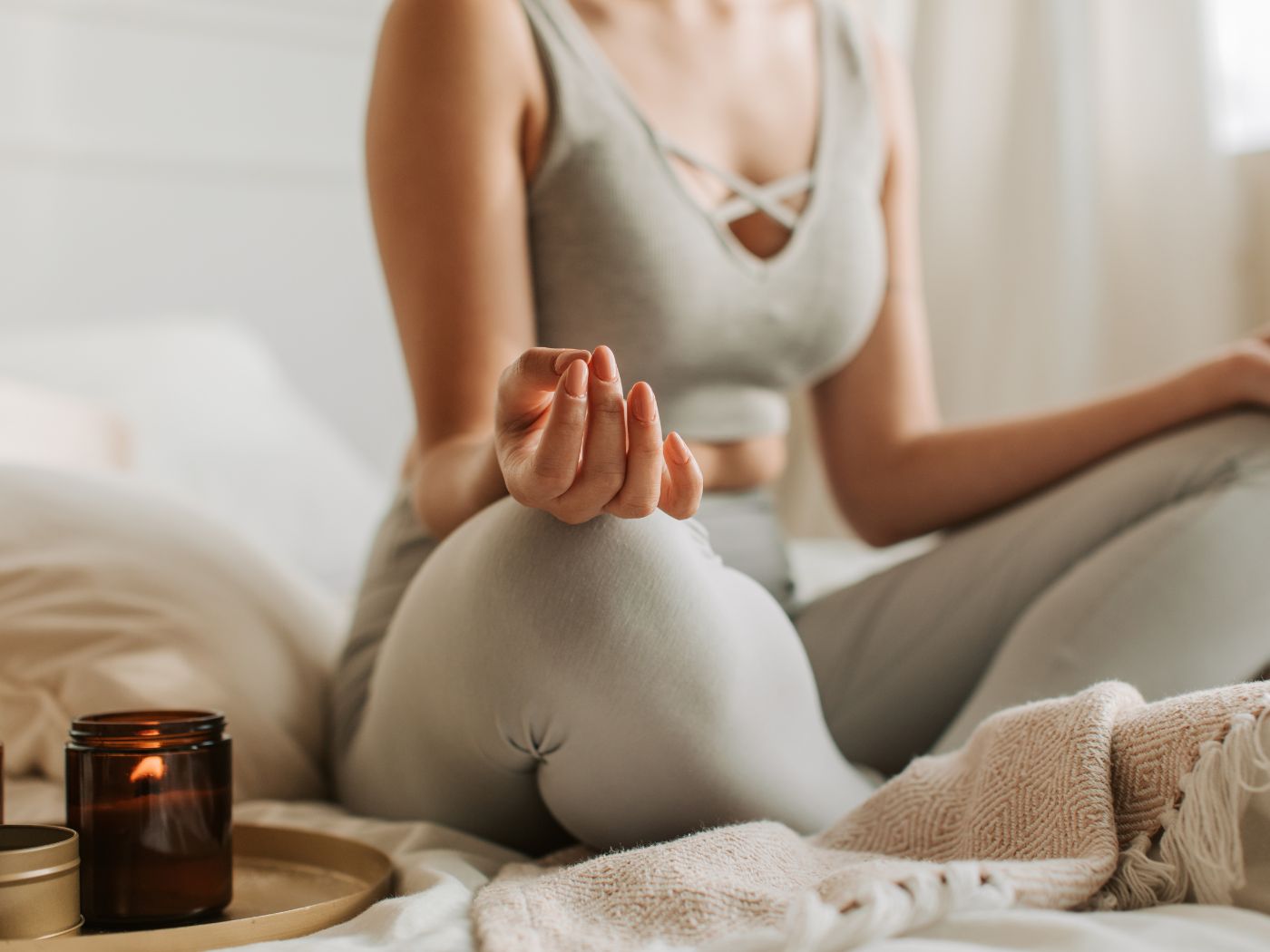 Woman meditating on a blanket next to a candle