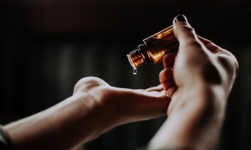 One Hand Dripping An Essential Oil From a Bottle Into The Other Hand