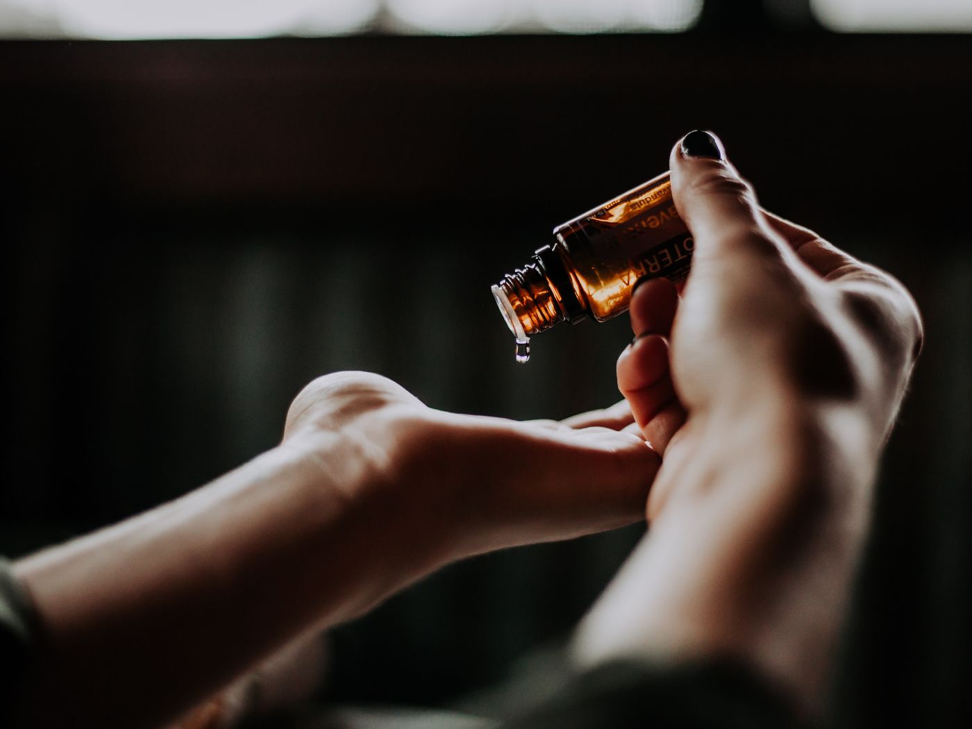 One Hand Dripping An Essential Oil From a Bottle Into The Other Hand