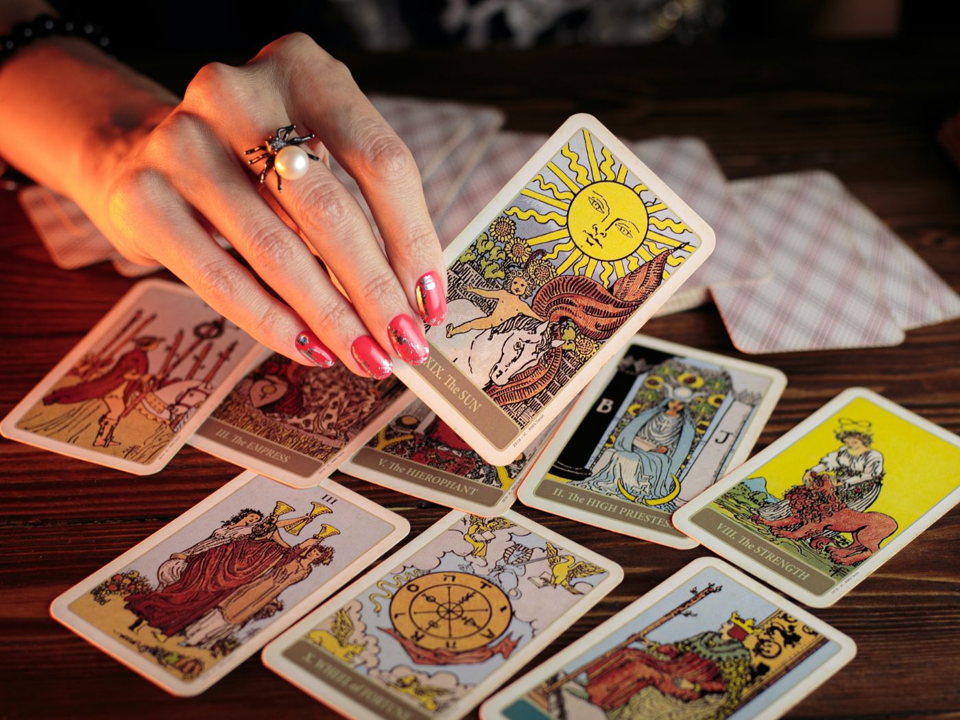 Manicured hand with red nails holding tarot card