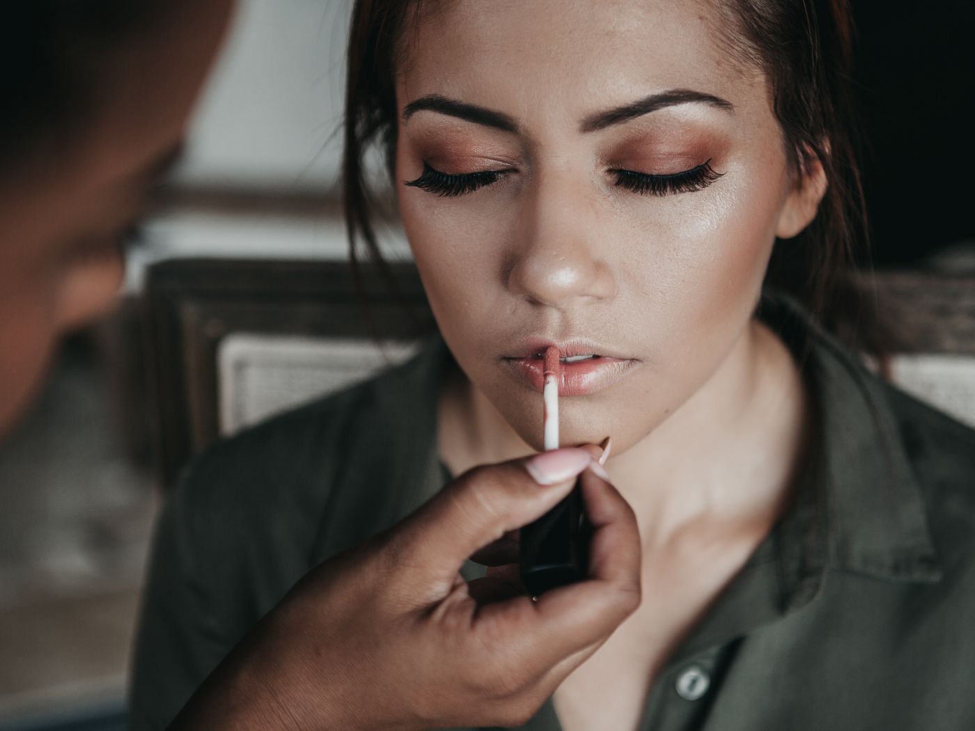 Make up artist applying lip gloss to a woman's lips