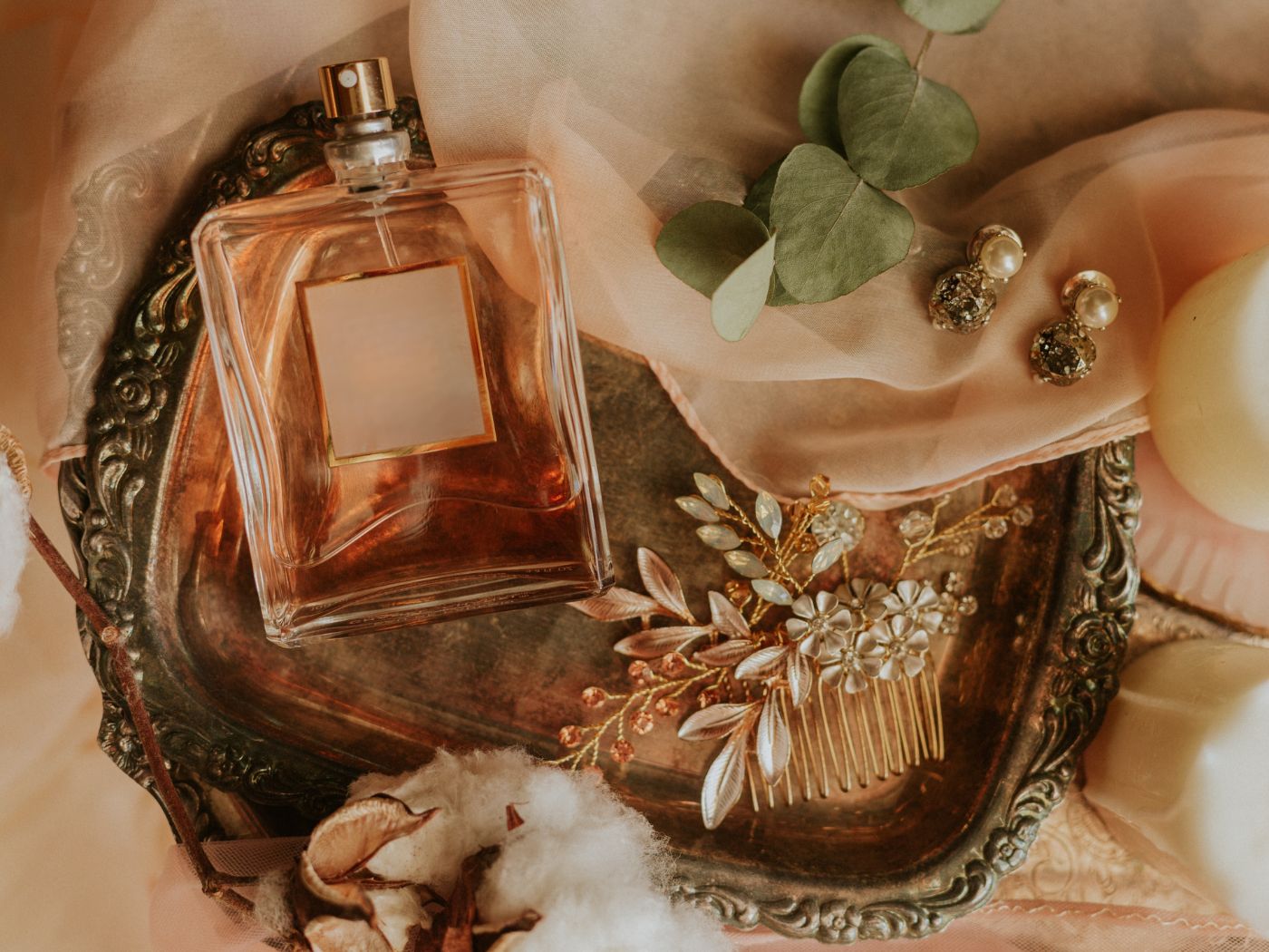 Perfume bottle nestled among tulle and jewelry and eucalyptus