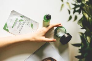 Left hand grabbing a jar of cream product over a tincture bottle