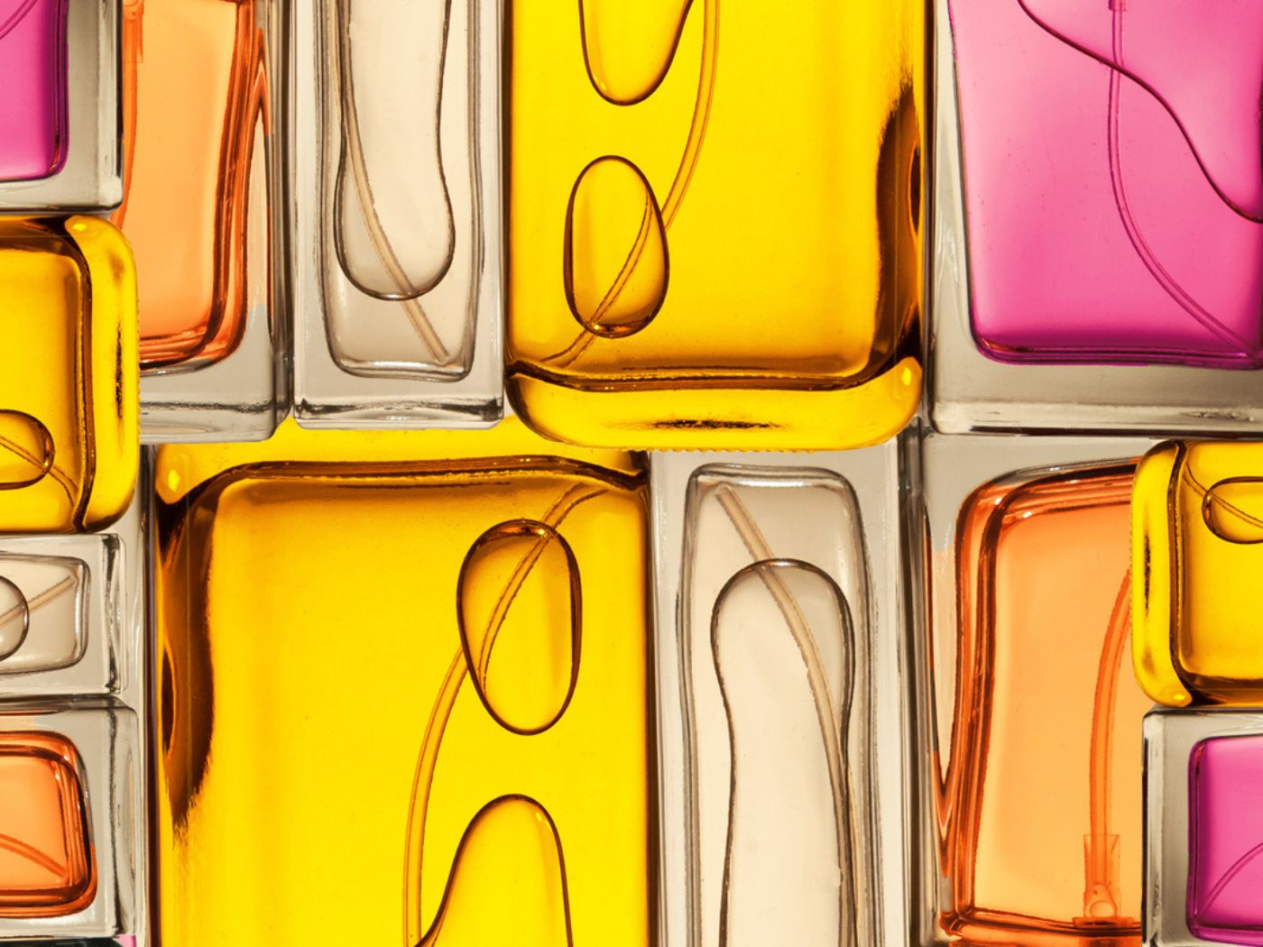 Close up of fragrance bottles in yellow, beige, orange, and pink