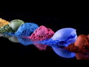 Small piles of colorful eyeshadows across a black table and background