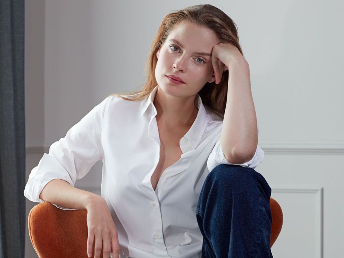 Woman seated in chair wearing a white shirt and jeans.