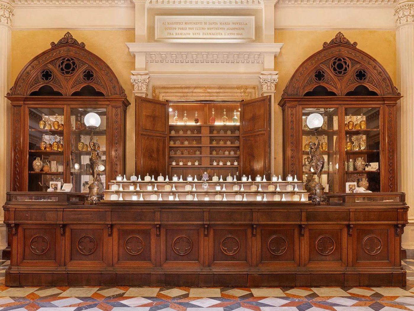 An old-fashioned apothecary-style counter, with old-fashioned glass perfume bottles on display and in glass cabinets in a historic old church building.