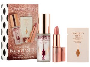 A gold-coloured beauty gift box with three products: an Airbrush Setting Spray in a bottle, A lipstick in a golden case and a sachet with a skincare sample.