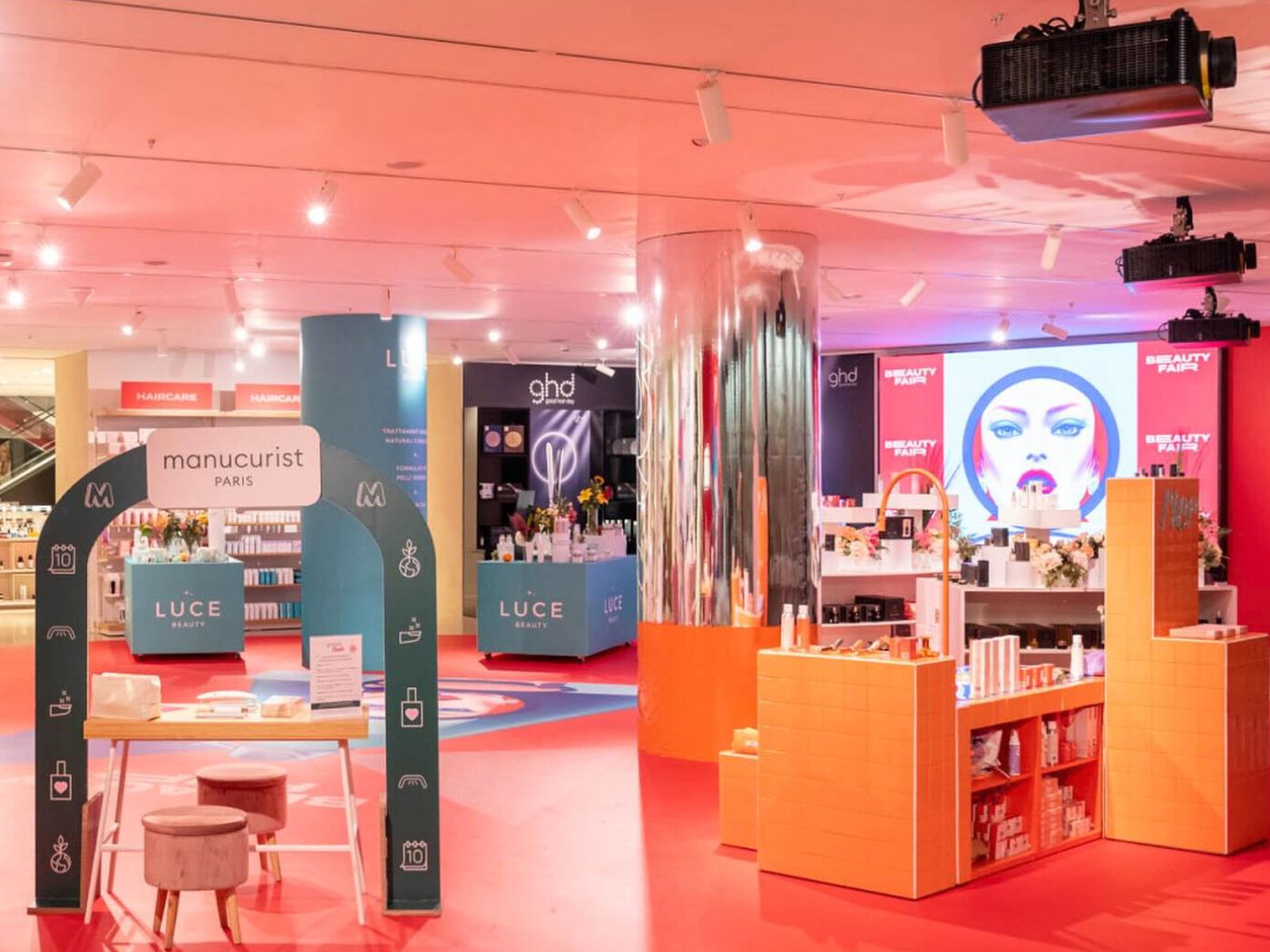 The interior of a beauty department within a store, with brightly coloured orange and pink counters and displays.