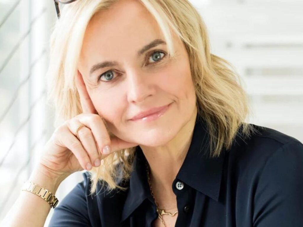 Woman with blonde hair wearing a black shirt smiling.