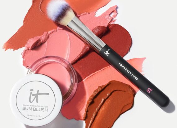Makeup swatches, a makeup brush and a pot of IT Cosmetics Sun Blush