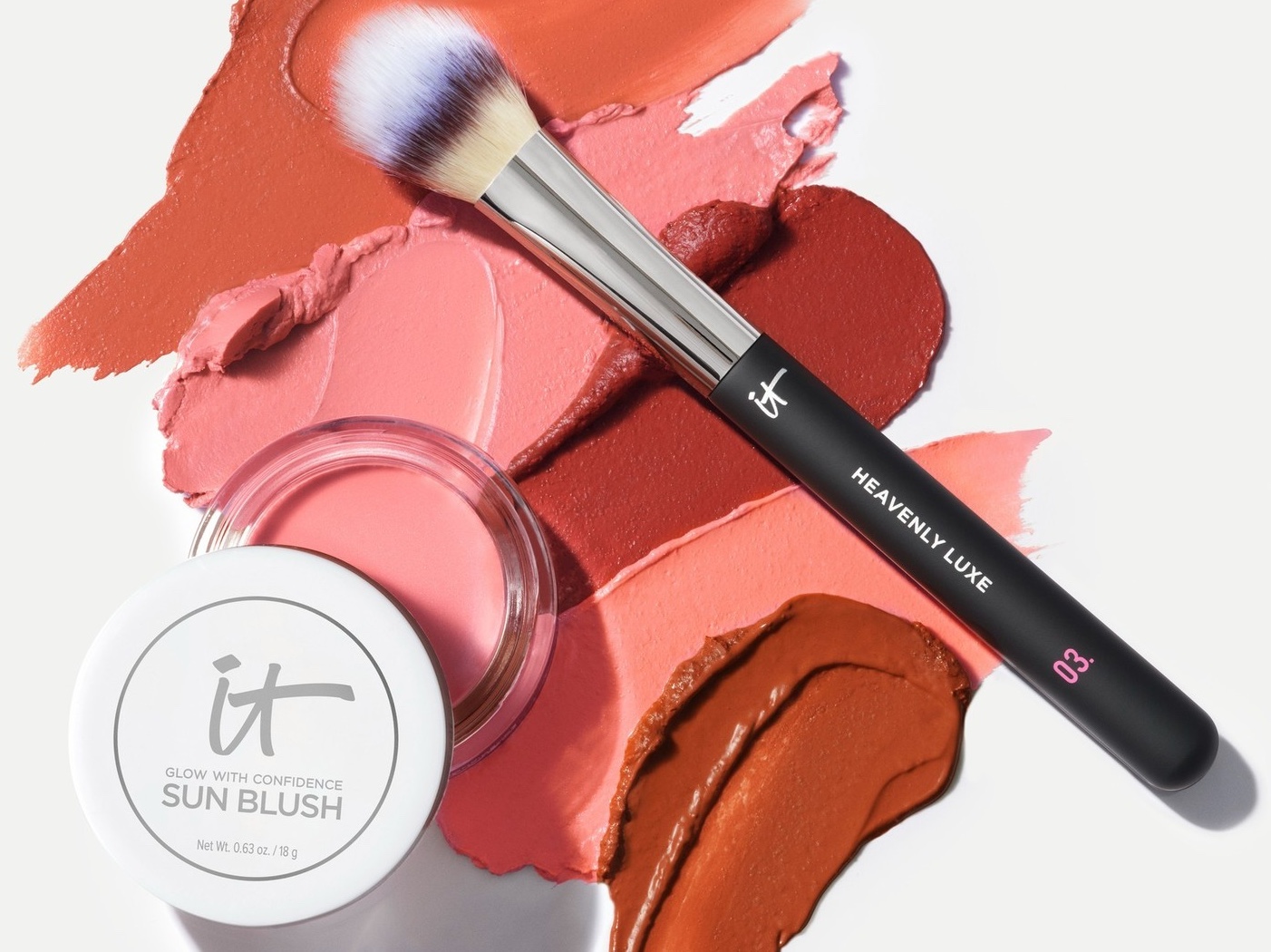 Makeup swatches, a makeup brush and a pot of IT Cosmetics Sun Blush