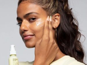 Model applying face cream to cheek.