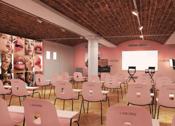 Pink themed classroom with chairs and a screen, and makeup photos on the walls.