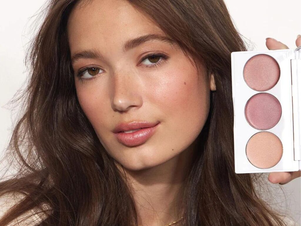 Woman holding a silver colored palette of three makeup colours