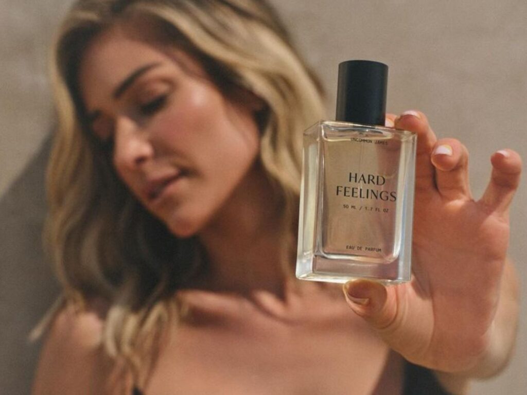 Woman holding a scent bottle with the words Hard Feelings on the bottle