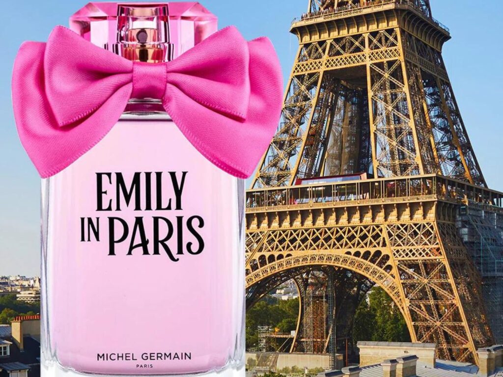 Emily In Paris perfume bottle. with a large pink bow, in front of the Eiffel Tower