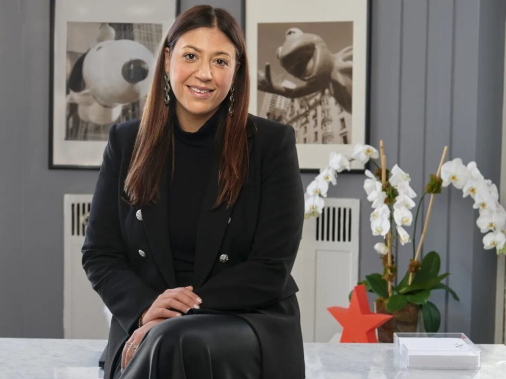Nata Dvir seated at a desk, wearing a black blazer and skirt.