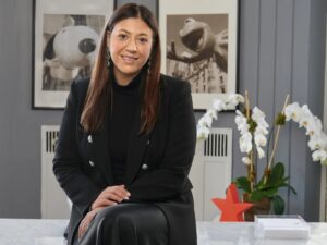 Nata Dvir seated at a desk, wearing a black blazer and skirt.