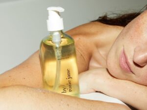 Girl in bath with bottle of By/Rosie Jane body wash