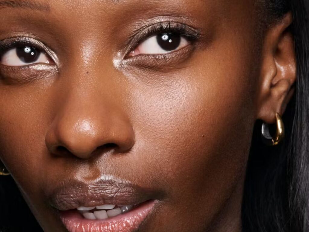 Close up of shimmery eyeshadow and smoky eyeliner and mascara on model wearing gold hoop earrings