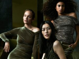 Three models wearing sparkling, dark green Donna Karan evening wear