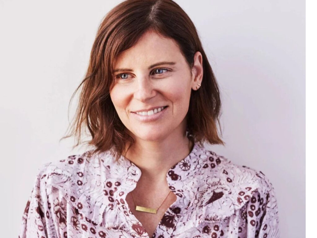 Photo of Courtney Somer wearing a lilac blouse and gold bar necklace