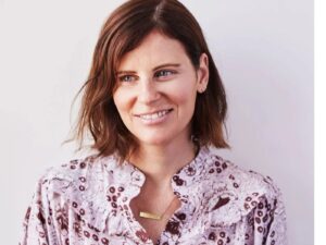 Photo of Courtney Somer wearing a lilac blouse and gold bar necklace