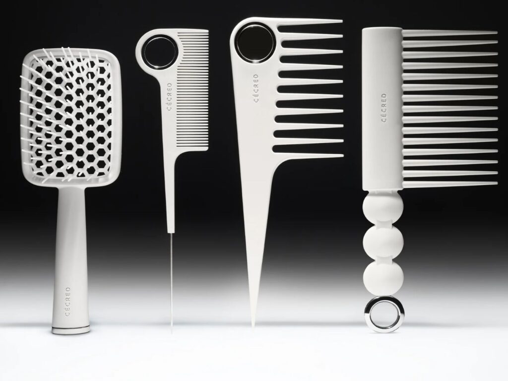 Four white styling combs and brushes standing upright, against a black background