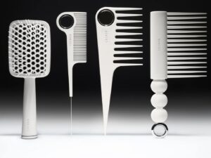 Four white styling combs and brushes standing upright, against a black background