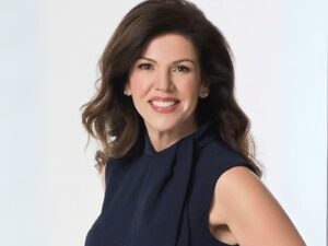 Sarah Schneider wears a sleeveless navy dress, smiling