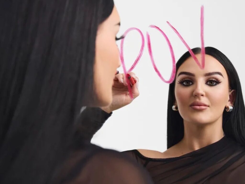 Mikayla Nogueira draws POV on a mirror in pink lipstick