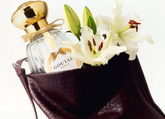 goutalparis Brown leather toe bag open with a bottle of Goutal Paris perfume inside and bunch of Lillies in full bloom