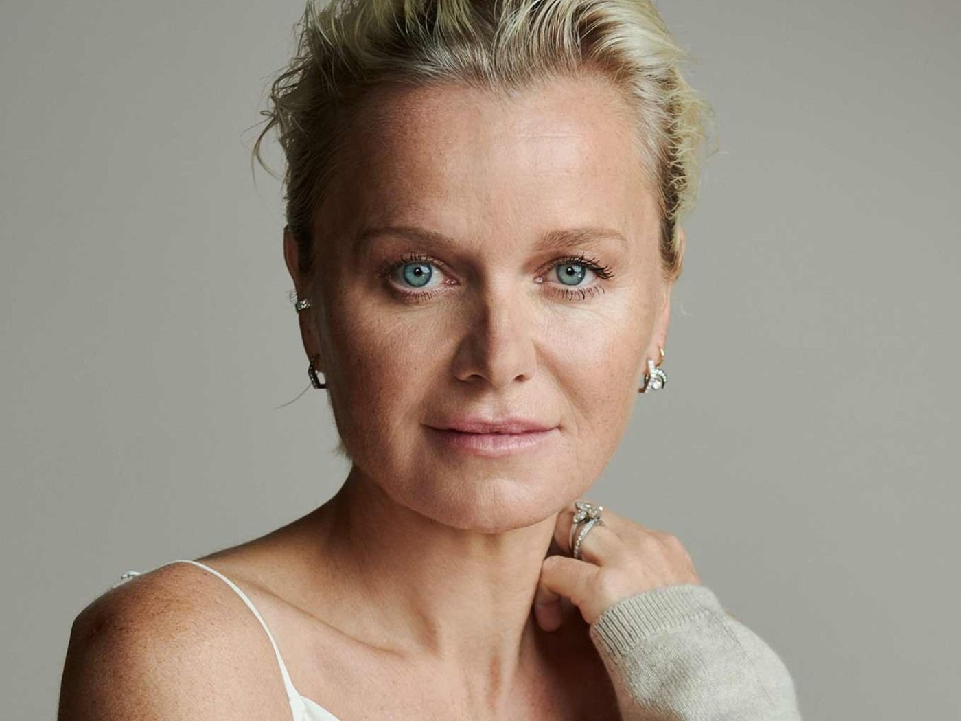 Dr. Barbara Sturm wearing a white camisole top and grey cardigan and silver earrings and rings.