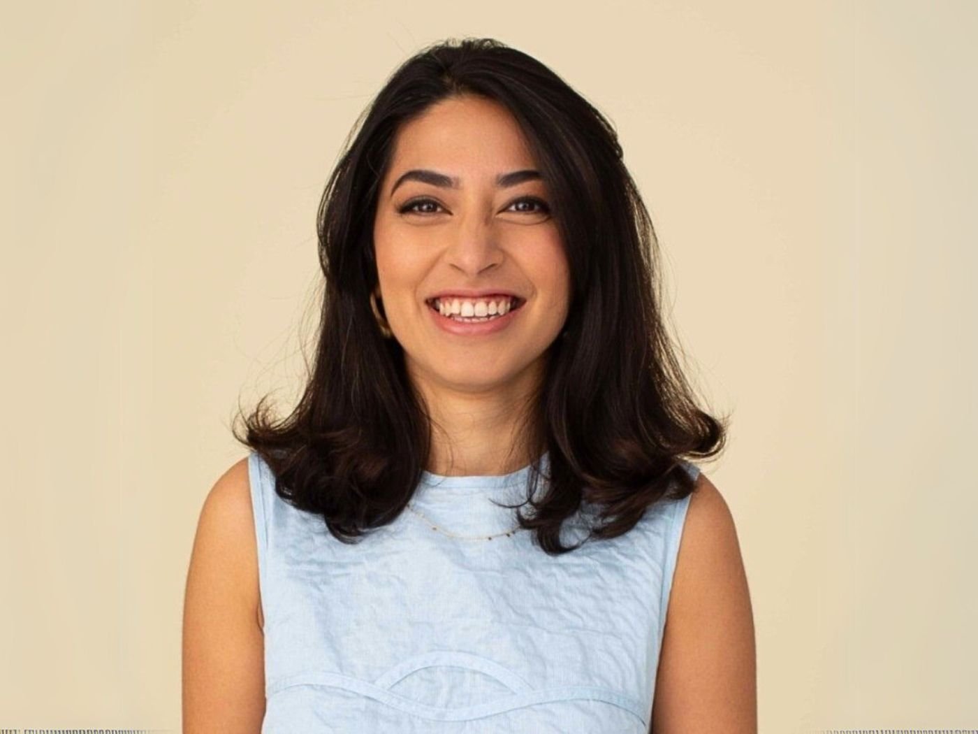 Insiya Jafferjee smiling, wearing a pale blue shift dress