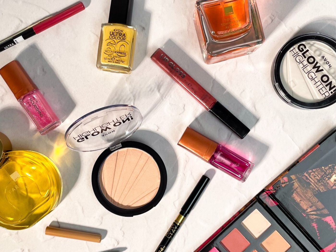 A range of Avon makeup and perfume laid out on a white counter