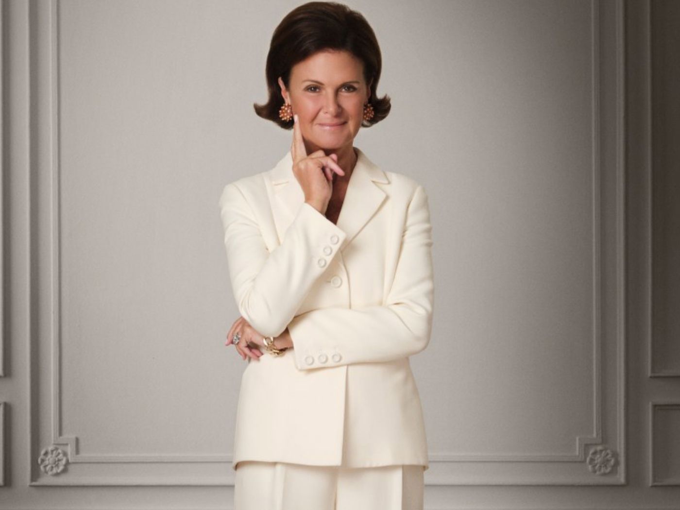 Laura Slatkin wears a white trouser suit, standing in front of a white wall