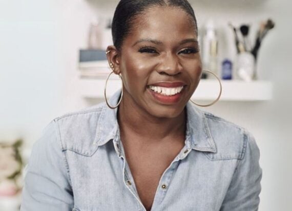 Funmi Fetto smiling, wearing a pale blue denim shirt and large gold hoop earrings