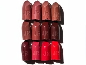 Different colored reds, browns and pinks lipstick bullets side by side on a white background