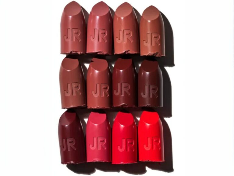 Different colored reds, browns and pinks lipstick bullets side by side on a white background