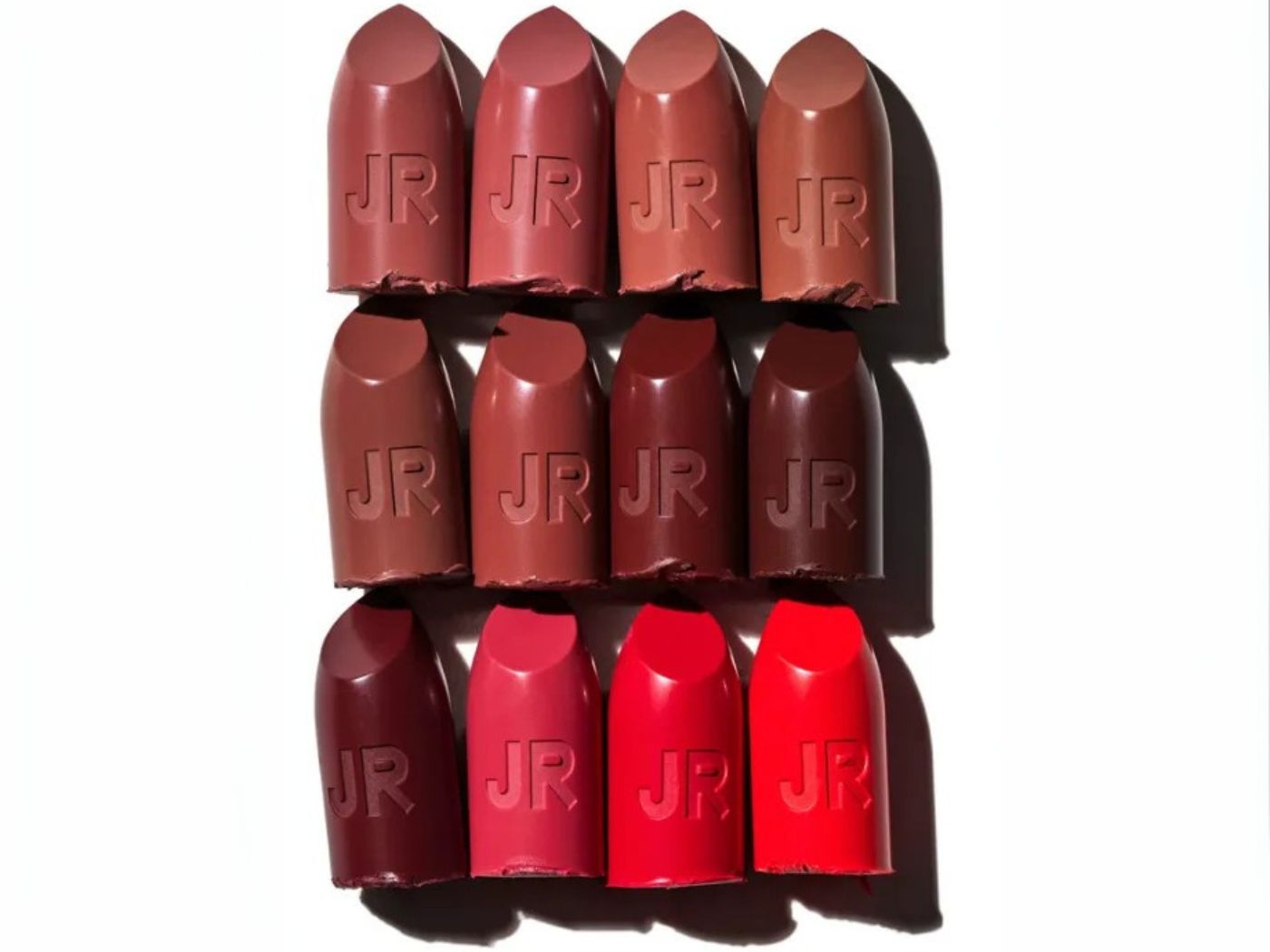 Different colored reds, browns and pinks lipstick bullets side by side on a white background