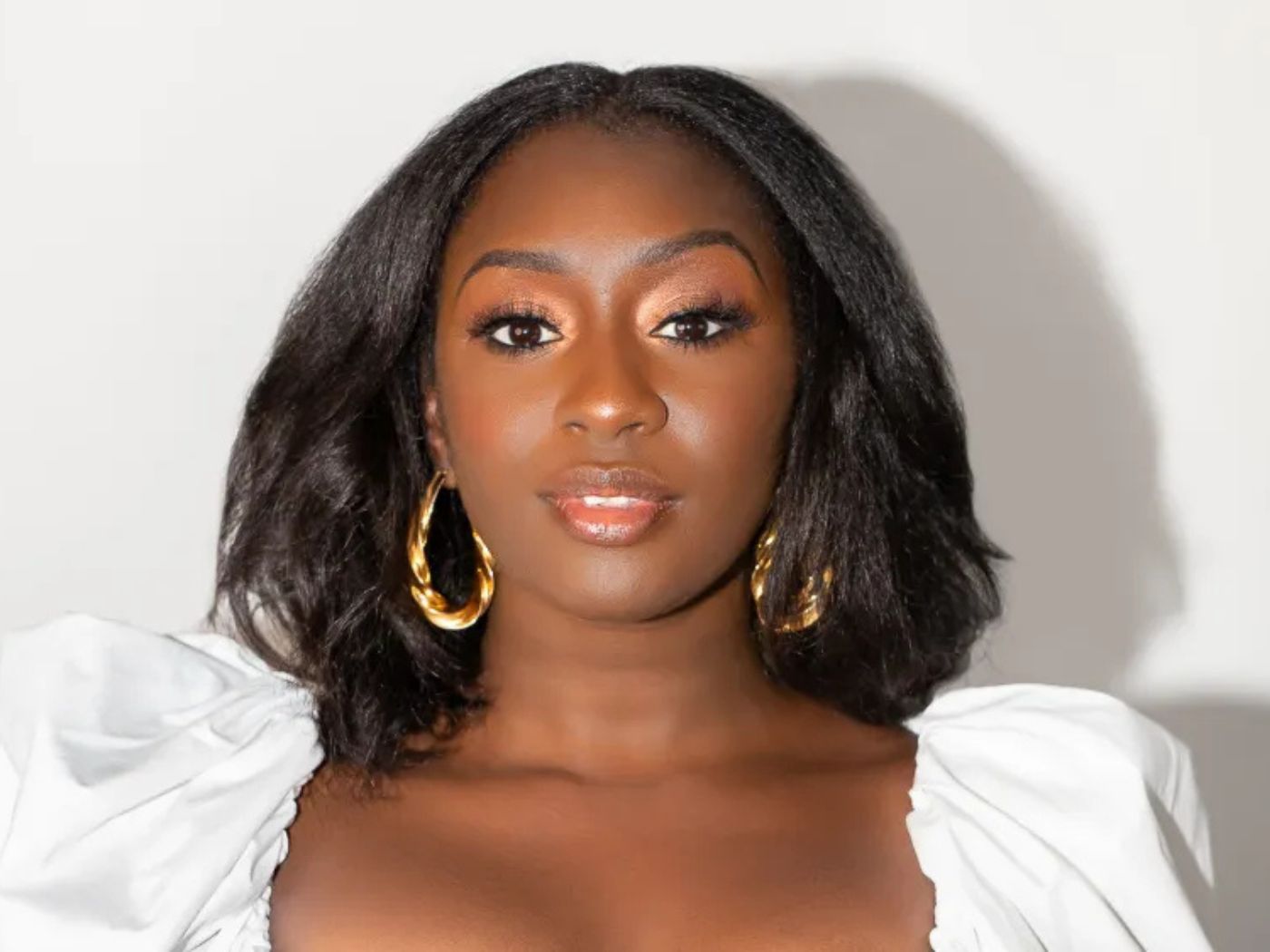 Diarrha N'Diaye wears a white puffy blouse and large gold hoop earrings