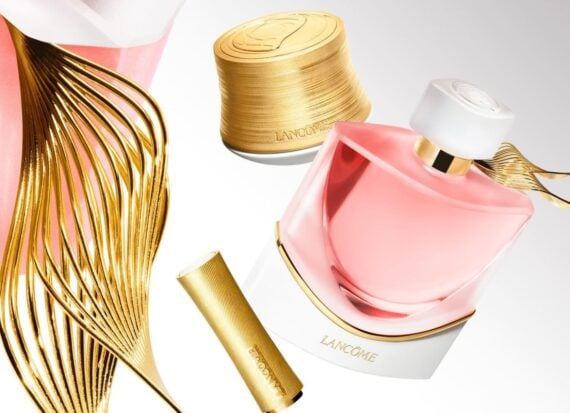 Lancôme A selection of gold and pink Lancôme perfume bottles, cream jars, and a lipstick on a white background.