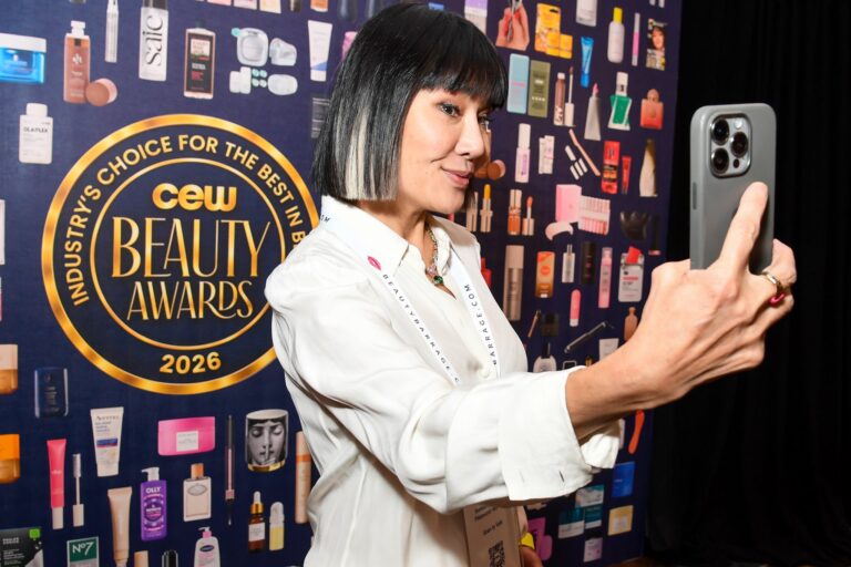 A guest photographing the CEW Beauty Awards finalists wall